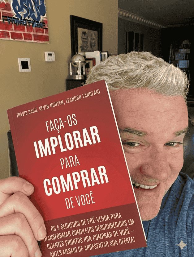 Travis Sago segurando o livro Faça-os Implorar Para Comprar De Você